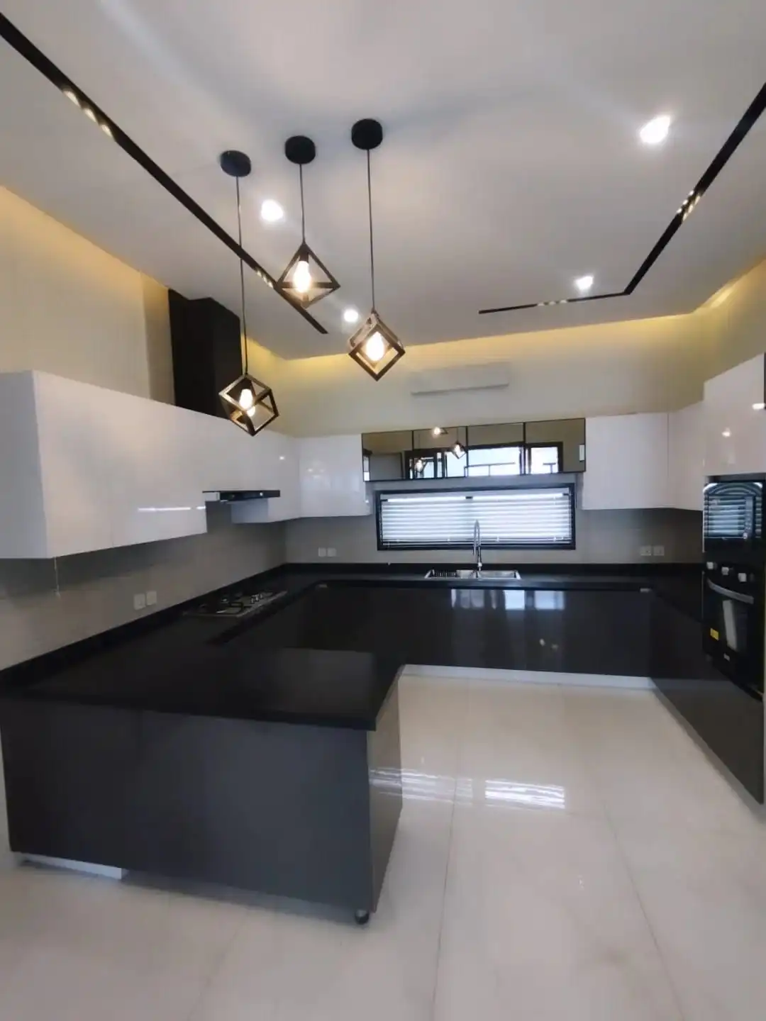Large U-shaped kitchen with black granite countertops white cabinets and pendant lights in Lake City M3 Lahore