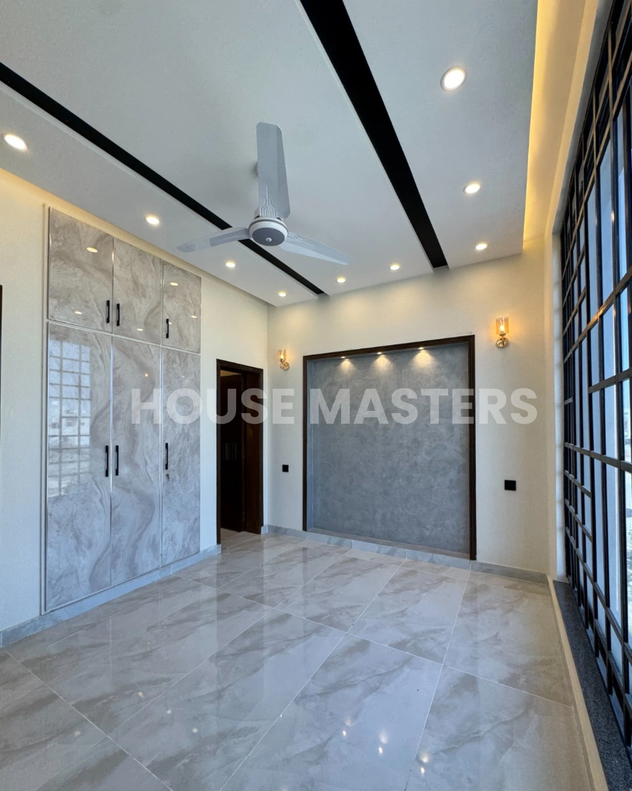 Premium Living Room – 5 Marla House, Bahria Orchard Lahore” Luxury 5 Marla house living room with large black-framed windows, ceiling fan, and ambient lighting in Bahria Orchard, Lahore.