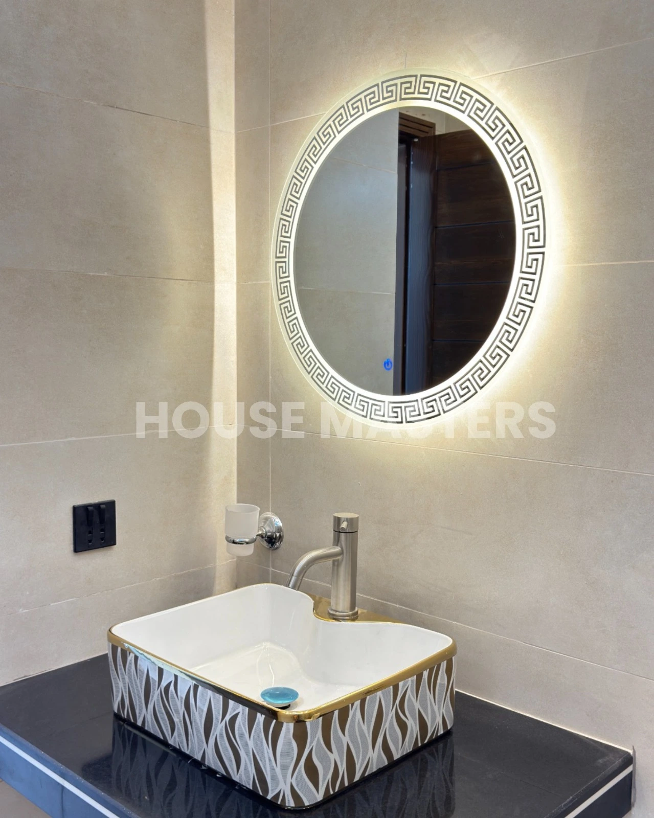 Premium Bathroom Design – 5 Marla House, Bahria Orchard Stylish bathroom with leaf-pattern accent wall, black countertop, and illuminated round mirror in 5 Marla luxury home, Bahria Orchard.
