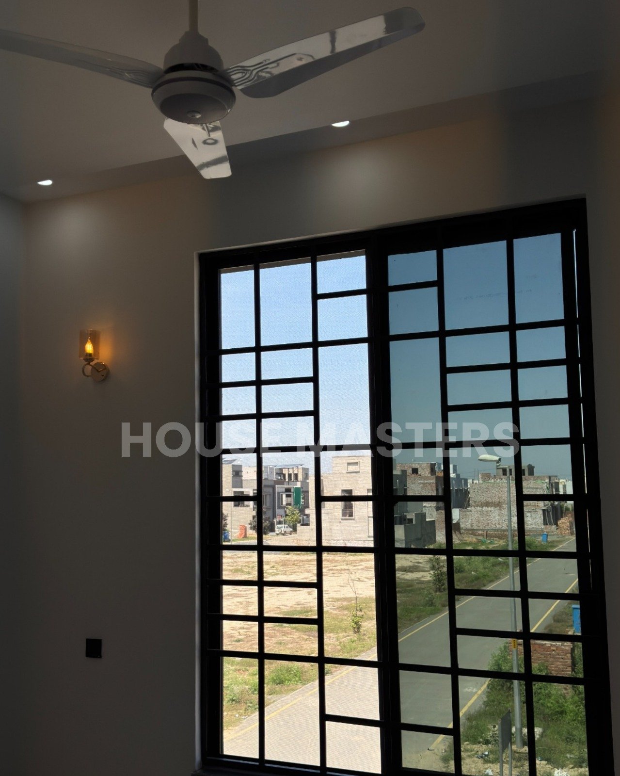 Premium Living Room – 5 Marla House, Bahria Orchard Lahore” Luxury 5 Marla house living room with large black-framed windows, ceiling fan, and ambient lighting in Bahria Orchard, Lahore.